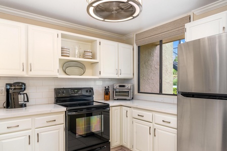 - Cook with ease using the glass top stove and handy countertop appliances - Classic white cabinets and open shelving create a clean coastal backdrop - Natural light pours in through the window for a cheerful cooking space