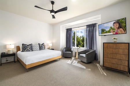 - Spacious bedroom with king bed and cozy seating nook beside a large window   - Natural light fills the room creating a bright and inviting atmosphere   - Wall mounted TV offers entertainment without leaving your retreat