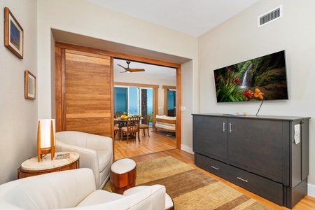 - Comfortable lounge corner with cream chairs and a flat screen TV for entertainment - Sliding wood door connects to dining area and stylish outdoor views - Neutral tones accented by wood details give the space a calm and welcoming feel