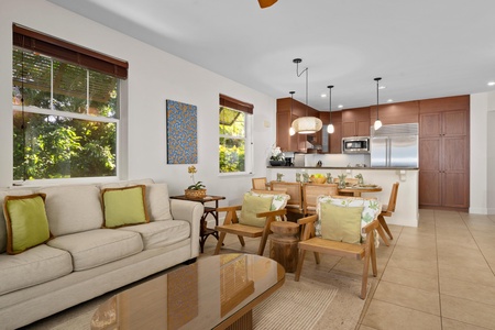 Your bright, open living space flows seamlessly from cozy seating to modern kitchen, with tropical garden views framing every moment.