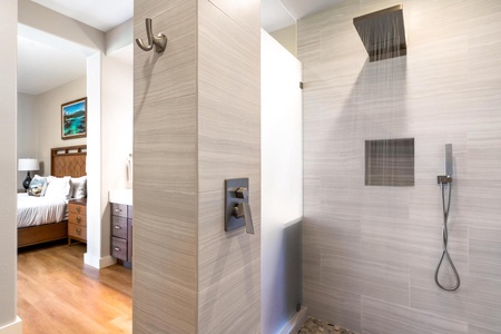 - Contemporary walk in shower with rainfall showerhead and pebble stone flooring - Neutral tile walls and built in shelf provide convenience and modern appeal - Open layout connects to vanity area for a cohesive bathroom experience