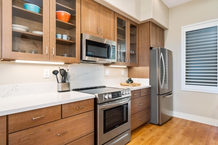 - Fully equipped cooking area with stainless steel appliances including range & microwave - Extra cabinetry with glass fronts provides storage and display for kitchen essentials - Bright countertops & under cabinet lighting keep the space fresh & function