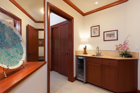 - Convenient kitchenette with sink, mini fridge, and warm wood cabinetry for added guest comfort - Soft lighting and framed wall art create a welcoming and stylish corner - Perfect for preparing light snacks or enjoying evening drinks