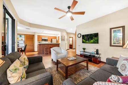 Unwind in your spacious living room with comfortable seating, tropical artwork, and an open kitchen perfect for gathering.