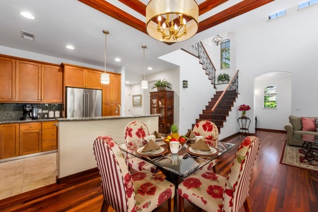 - Dining area with glass top table and floral upholstered chairs for four - Open floor plan flows seamlessly into the kitchen and staircase - Warm wood flooring and chic lighting create a welcoming ambiance