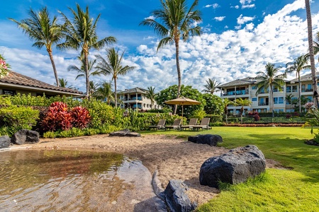 Sandy beach area with palm trees and lounge chairs beside calm waters.