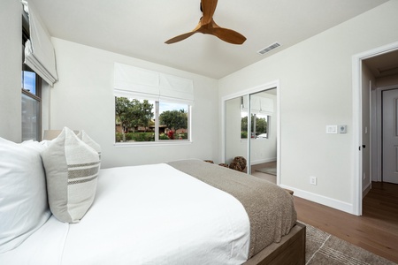 Unwind in your serene bedroom where crisp white linens meet modern comfort, with garden views and a ceiling fan keeping you cool.