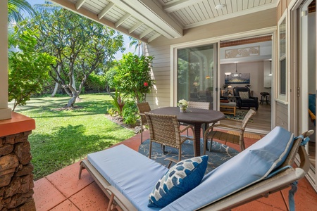 Relax on your private covered patio with plush loungers and dining space, overlooking the lush garden where tropical trees create your peaceful retreat.