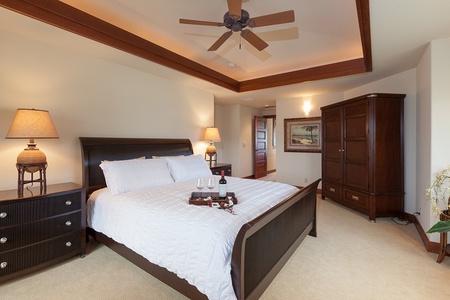 - Spacious bedroom with king bed dressed in crisp white linens   - Warm wood furniture and ceiling fan create a relaxing retreat   - Tray with wine and treats adds a welcoming touch for guests