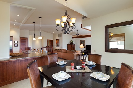 - Elegant dining space with dark wood table and leather chairs for six   - Stylish chandelier casts a warm glow over place settings and décor   - Open layout connects to kitchen and living area for seamless hosting