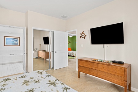Primary bedroom retreat features a wall-mounted TV, ceiling fan, and an ensuite bathroom for your comfort.