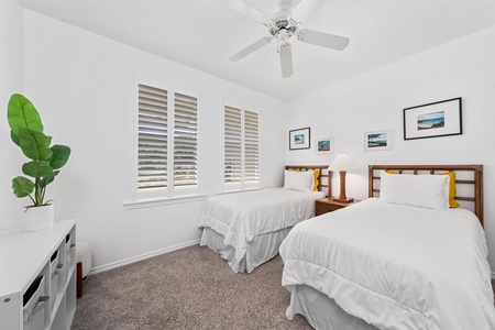 - Bright twin bedroom perfect for kids or friends with soft carpet and fresh white linens - Shuttered windows bring in light while providing privacy and comfort - Framed artwork and bedside lighting add charm to this restful retreat