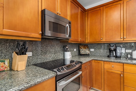 - Close up of stainless steel range and built in microwave framed by wood cabinets - Granite backsplash and counters add elegance to the space - Fully equipped for preparing delicious home cooked meals