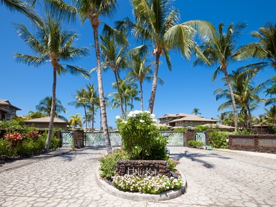 Grand entrance with floral landscaping and towering palms.