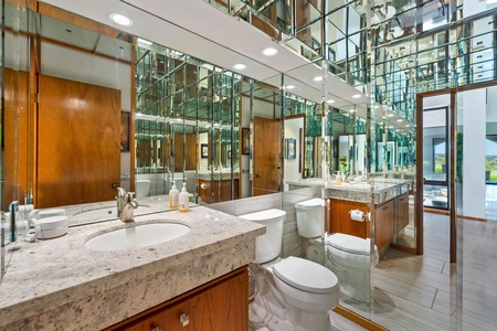 - Unique full bathroom with granite vanity and floor to ceiling mirrors for dramatic flair - Wood cabinetry adds warmth to the sleek and reflective design - Perfect for getting ready in style with great lighting and plenty of counter space