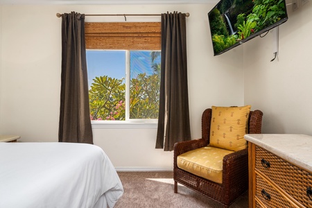 Your bright bedroom features a cozy reading nook and tropical garden views through bamboo blinds.