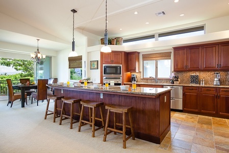- Bright gourmet kitchen with large island and four wooden bar stools   - Stainless steel appliances and pendant lighting create a modern touch   - Open design flows seamlessly into dining and living spaces for hosting