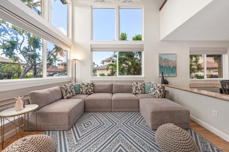 Sink into this spacious sectional where floor-to-ceiling windows frame tropical views and natural light fills your airy living space.