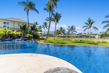 Shimmering blue pool surrounded by beautiful green lawns.