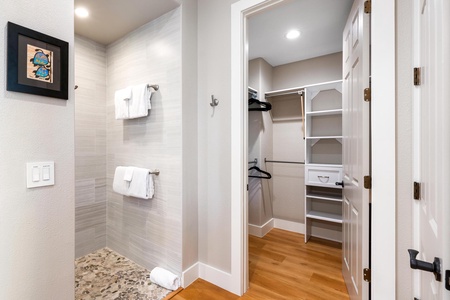 - Walk in shower with neutral tile walls and pebble stone flooring for a spa like feel - Towel hooks and racks provide convenience within easy reach of the shower area - Doorway leads directly into a spacious walk in closet with built in shelving and stor