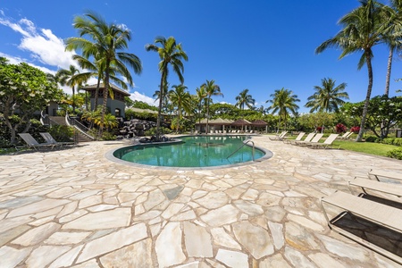 Tropical paradise awaits with this stunning pool area surrounded by swaying palm trees and lush landscaping under brilliant blue skies.
