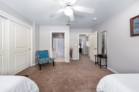 - Spacious twin room offers direct access to a full bathroom for convenience - Teal patterned accent chair and full length mirror enhance the comfort - Neutral tones and open layout provide a calm space for any guest