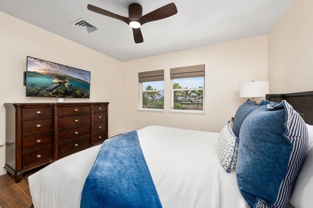 Drift off in your cozy bedroom featuring tropical ocean views, plush bedding, and a ceiling fan keeping you comfortable all night long.