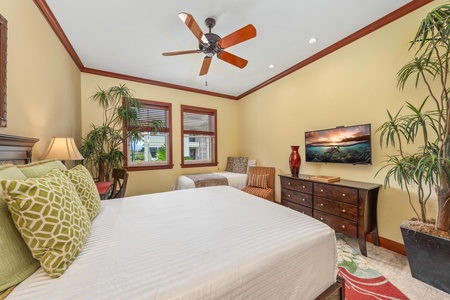 Drift off to sleep beneath a gentle ceiling fan in this inviting bedroom, where crisp linens and tropical greenery create a soothing retreat.