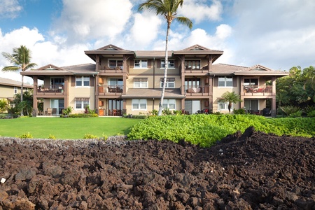 Beautiful lanai facing building bordered by lava rock and greenery.