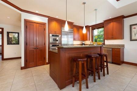 - Kitchen island with seating for three and granite countertop for meal prep   - Stainless steel fridge, wall ovens, and wood cabinetry provide style and function   - Open layout keeps the chef connected to the dining and living areas