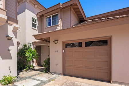 Welcoming two-story entrance with charming architectural details, landscaped walkway, and private garage. The beige and cream tones create a warm first impression as you arrive at this coastal retreat.
