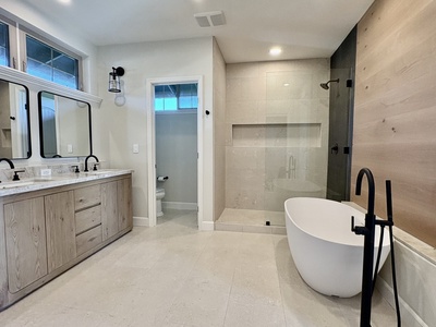 Limestone floors, a luxurious walk-in shower, leathered quartzite countertops, and rich basalt and oak accents create a true spa retreat