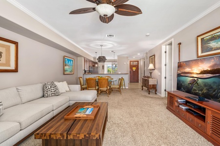 Relax in your spacious living area with plush seating, tropical ceiling fans, and ocean-themed artwork that brings Hawaiian charm to every moment.