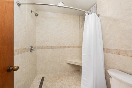 Step into your elegant tiled shower with rainfall showerhead and built-in bench for a spa-like bathing experience.
