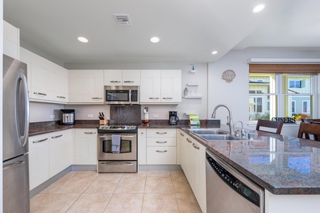 - Whip up island meals in a fully equipped kitchen featuring modern essentials - Stainless steel oven, microwave, fridge, and coffee setup for easy dining - Crisp white cabinets, tile floors, and granite counters blend style and function