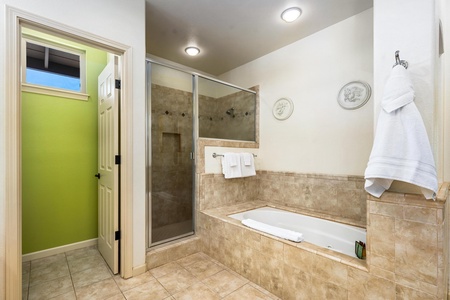 Spacious bathroom features a glass walk in shower and a tiled soaking tub.