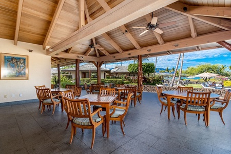Covered outdoor dining area with wooden tables and ceiling fans for comfort.