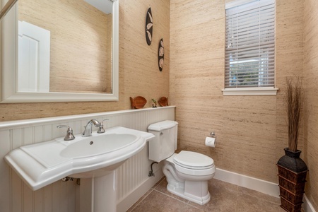Step into your elegant powder room featuring warm grasscloth wallpaper and crisp white wainscoting for a refined coastal feel.