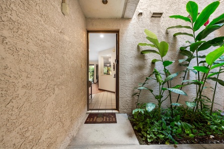 A welcoming entrance with lush tropical plants creates a peaceful arrival at this charming property.