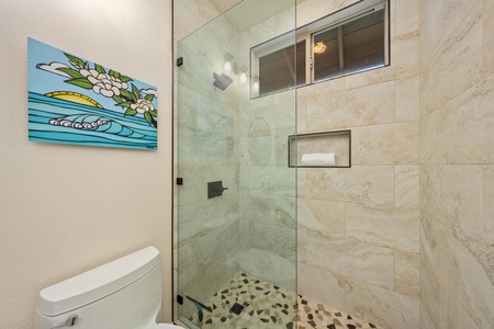 Step into your spa-like bathroom featuring a stunning glass-enclosed shower with natural stone walls and mosaic flooring.