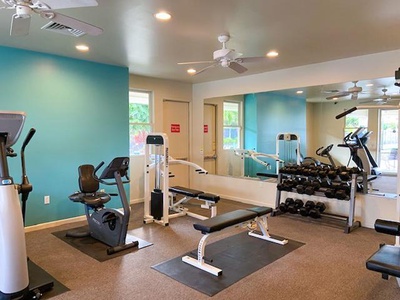 Bright fitness room with cardio and strength training equipment.