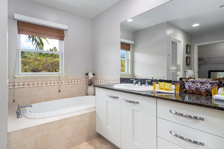 - Unwind in the deep soaking tub surrounded by neutral tile and soft lighting - Granite countertop and sleek fixtures offer a clean and functional setup - Bright window brings in natural light for a spa inspired bathroom feel