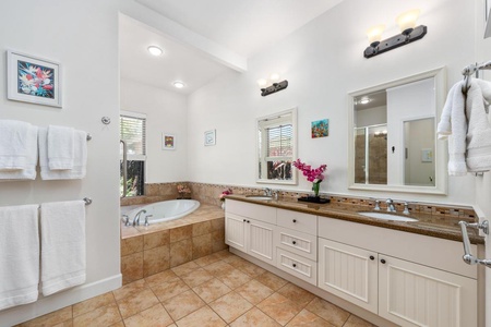 - Soak your stress away in a large corner tub set beneath a sunny window - Spacious tile floored bathroom with double vanity and generous mirrors - Bright lighting, floral accents, and natural tones create a calming vibe