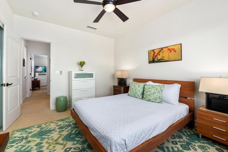 - Light filled bedroom with sleek wood bed and coordinated furniture - Elegant rug, soft lighting, and colorful art accent the modern style - Dresser and side tables offer functionality without cluttering the space