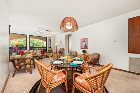 Your tropical dining space features rattan chairs around a glass table, perfect for sharing meals while enjoying garden views through floor-to-ceiling windows.