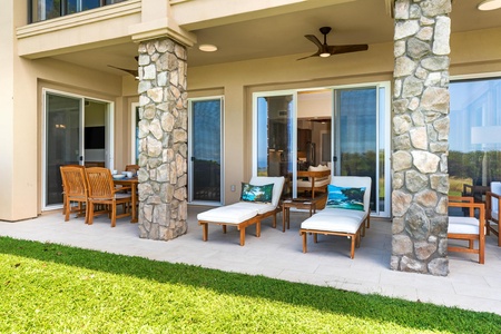 - Covered patio with cushioned loungers & dining area offering a relaxing outdoor retreat - Stone pillars & ceiling fans provide shade and comfort for enjoying the fresh air - Sliding glass doors offer seamless flow between indoor living & open green lawn