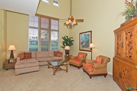 - Bright living room with sectional sofa, armchairs, and tall windows - Ceiling fan and beautiful greenery add comfort and a touch of nature - Glass coffee table and warm decor create a cozy gathering spot