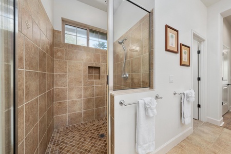 Step into your spa-like bathroom featuring a spacious walk-in shower with elegant tile work and fresh towels waiting for your arrival.
