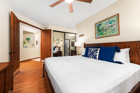 Your peaceful bedroom features a comfortable bed with tropical artwork, warm wood accents, and ceiling fan for ultimate relaxation.