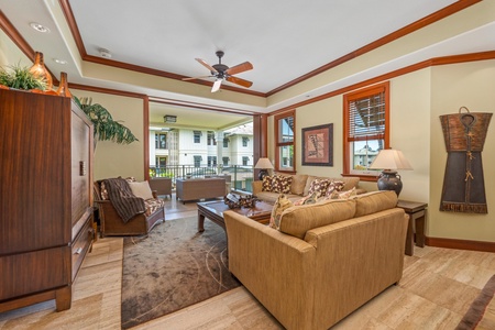 Unwind in your spacious living area with elegant wood accents, comfortable seating, and a ceiling fan to keep you cool—your perfect retreat opens to a private balcony.